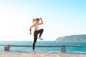 jong fit vrouw jumping hoog Aan strand met zonsondergang, actief Kaukasisch jong volwassen vrouw training met , lichaamsgewicht opleiding oefening voor vrouw, zelf motivatie foto