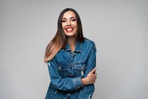 mooi Kaukasisch meisje in een denim jasje poseren in de studio Aan een wit achtergrond. foto