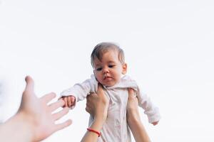 moeder handen gooien omhoog de hoog lucht blij baby. buitenshuis gezond kind werkzaamheid, actief levensstijl en hebben pret Aan familie zomer vakantie foto