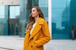 bedrijf vrouw gekleed geel jas staand buitenshuis corporatief gebouw achtergrond foto