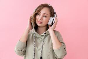 vrouw luister muziek- hoofdtelefoons roze achtergrond studio schieten foto