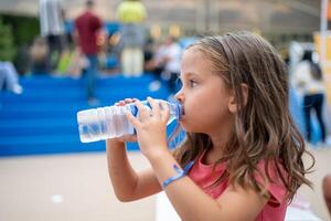 kind drinken water van plastic fles buitenshuis foto