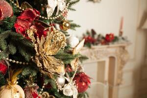 dichtbij omhoog van decoratie rood en goud versierd Aan groen Kerstmis boom of pijnboom met onscherp wazig gemaakt foto