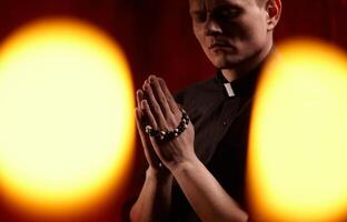 jong volwassen Kaukasisch Katholiek priester Aan donker rood achtergrond foto