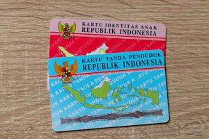 Jakarta, Indonesië, 2024 - de Indonesisch identiteit kaart en de Indonesisch kind identiteit kaart geïsoleerd Aan houten achtergrond foto