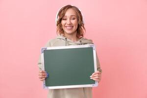 vrouw Holding leeg schoolbord over- roze achtergrond foto