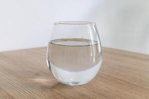 een glas van water Aan houten tafel foto