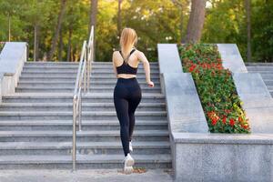 sport en geschiktheid. fit vrouw rennen omhoog de stappen zomer zonnig ochtend- Kaukasisch atletisch vrouw jogging buitenshuis cardio opleiding actief gezond levensstijl foto