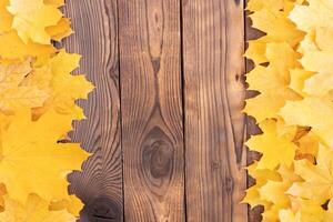 herfst bladeren kader Aan houten achtergrond top visie vallen grens geel en oranje bladeren wijnoogst hout tafel kopiëren ruimte voor tekst. foto