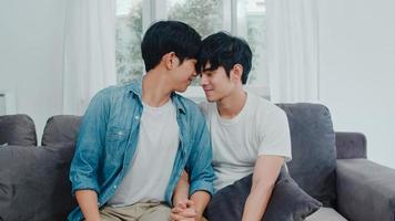jong aziatisch homopaar knuffel en kus thuis. aantrekkelijke aziatische lgbtq-trots mannen gelukkig ontspannen brengen romantische tijd samen door terwijl ze op de bank liggen in het woonkamerconcept. foto