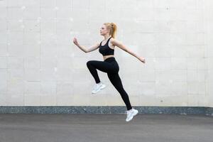 sport en geschiktheid concept jong volwassen Kaukasisch vrouw atleet jumping hoog buitenshuis grijs staart muur achtergrond foto