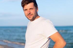 Kaukasisch Mens staand Aan de zee strand dressing wit overhemd foto