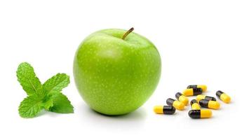 Groene appelmunt en pillencapsules die op witte achtergrond worden geïsoleerd