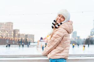 gelukkig winter tijd in groot stad charmant meisje staand straat gekleed grappig pluizig hoed. genieten van sneeuwval, uitdrukken positiviteit, glimlachen naar camera foto