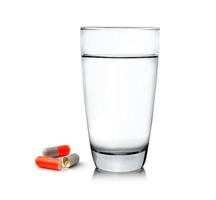 glas water en pillen geïsoleerd op een witte achtergrond foto