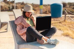 reiziger met haar laptop zittend Aan de middellandse Zee kust van Barcelona foto