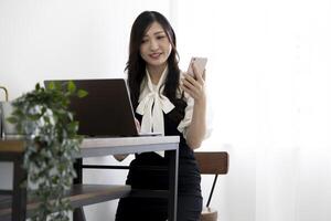 een Japans vrouw controle smartphone door afgelegen werk in de huis kantoor foto