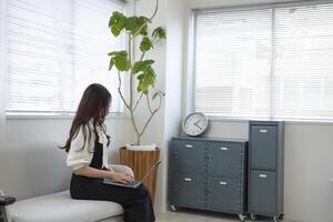 een Japans vrouw controle smartphone door afgelegen werk in de huis kantoor foto