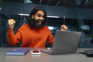 Mens opgewonden met computer in kantoor foto