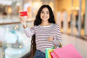 gelukkig jong Indisch vrouw met aankopen en credit kaart foto