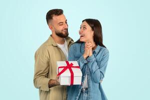 vrolijk Kaukasisch Mens geeft verpakt Cadeau doos feliciteren vrouw, studio foto