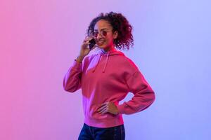 elegant zwart vrouw pratend Aan telefoon met neon backdrop foto