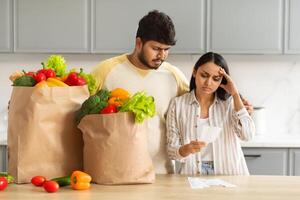 gefrustreerd Indisch paar controle rekeningen na kruidenier boodschappen doen foto