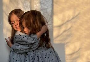portret van gemengd ras tweeling baby meisjes knuffelen elk ander. gelukkig broers en zussen dag. foto