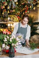 een vrouw in haar bloemist winkel verzamelt boeketten van bloemen. de concept van een klein bedrijf. boeketten van tulpen voor de vakantie Aan maart 8. foto