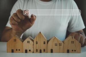 hand- aanraken zoeken bar voor informatie gegevens over huis Aan top van een model- hout huis. foto