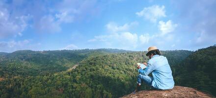 Aziatisch Mens reizen kom tot rust in de vakantie. stoelen kom tot rust lezen boeken Aan rotsachtig kliffen. Aan de moutain zomer. in Thailand foto