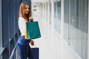 mooi jong vrouw met Tassen in boodschappen doen centrum foto