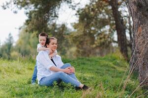 gelukkig jong moeder is spelen met haar baby in een park Aan een groen gazon. geluk en harmonie van familie leven. Super goed familie vakantie. mooi zo weekend. moeders dag. vakantie. de concept van een gelukkig familie foto