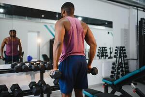 gewicht opleiding Afrikaanse aan het doen bodybuilding in Sportschool. foto