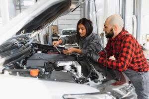 auto auto reparatie onderhoud centrum. monteur onderzoeken auto motor. vrouw monteur werken in haar werkplaats. auto onderhoud bedrijf concept. pro auto vrouw monteur nemen zorg van voertuig. foto