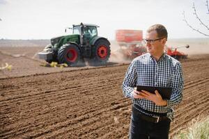 boer in veld- onderzoeken zaaien en Holding tablet in zijn handen. foto