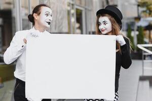 uw tekst hier. acteurs mimespelers Holding leeg wit brief. kleurrijk portret met grijs achtergrond. april dwazen dag foto