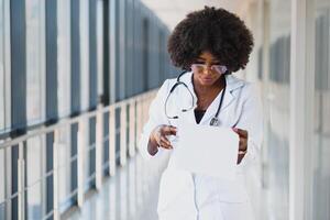 detailopname hoofdschot portret van vriendelijk, glimlachen zelfverzekerd vrouw gezondheidszorg professioneel met laboratorium jas, armen gekruiste Holding bril. geïsoleerd ziekenhuis kliniek achtergrond. tijd voor een kantoor bezoek foto