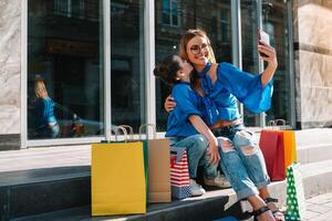 uitverkoop, consumentisme en mensen concept - gelukkig jong Dames haar dauther met boodschappen doen Tassen wandelen stad straat foto