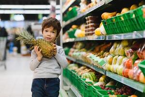 mooi jongen met ananas in supermarkt foto