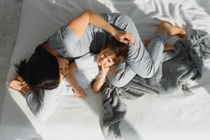 moeder spelen met haar weinig schattig zoon in de ochtend- in slaapkamer. gelukkig familie tijd. foto