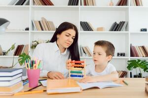 vrouw privaat tutor helpen jong leerling met huiswerk Bij bureau in helder kind kamer foto