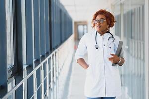 Afrikaanse Amerikaans verpleegster met klembord in ziekenhuis foto