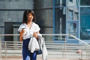 bedrijf en mensen concept - jong glimlachen Afrikaanse Amerikaans zakenvrouw met koffie kop in stad foto