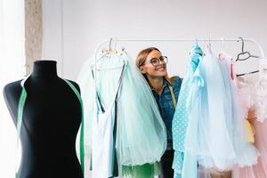 aantrekkelijk vrouw mode ontwerper is werken in haar werkplaats. elegant vrouw in werkwijze van creëren nieuw kleren verzameling. foto
