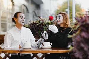 mime vent en meisje in cafe drinken koffie. mime in voorkant van Parijs cafe acteren Leuk vinden drinken thee of koffie. foto