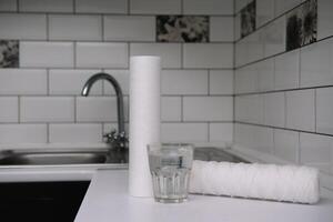 water filters. koolstof inktpatronen en een glas Aan een wit keuken achtergrond. huishouden filtratie systeem. foto