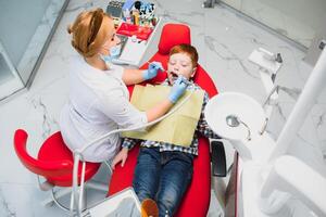 pediatrisch tandarts onderzoeken een weinig jongens tanden in de tandartsen stoel Bij de tandheelkundig kliniek foto