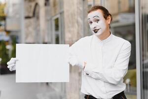 uw tekst hier. acteur mime Holding leeg wit brief. kleurrijk portret met grijs achtergrond. april dwazen dag foto