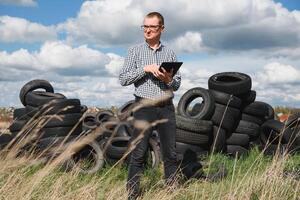 eco-activist Bij de stortplaats van gebruikt auto banden berekent milieu schade. natuur behoud concept foto